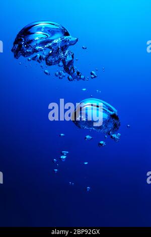 Luftblasen, die im blauen Wasser schwimmen. Unterwasserszene. Stockfoto