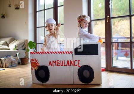 Zwei kleine Kinder mit Arztuniformen zuhause, spielend. Stockfoto