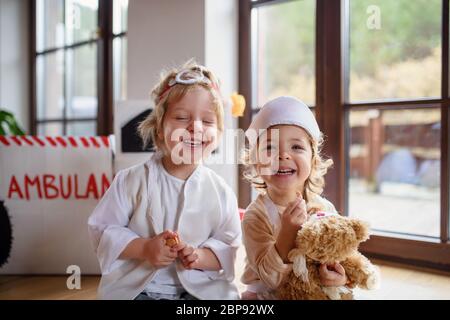 Zwei kleine Kinder mit Arztuniformen zuhause, spielend. Stockfoto