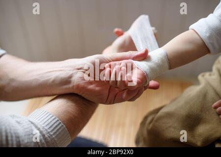 Vater, der Verband auf kleine verletzte Kleinkind Kind zuhause. Stockfoto