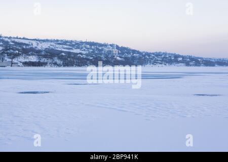 Winterlandschaft mit Dorf und gefrorenem See Stockfoto