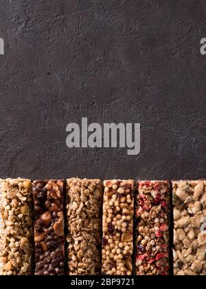 Müsliriegel mit kopieren. Satz von verschiedenen Granola Bars auf schwarzem Hintergrund. Flache Freiheitsgrad. Top View oder flach. Vertikale. Stockfoto