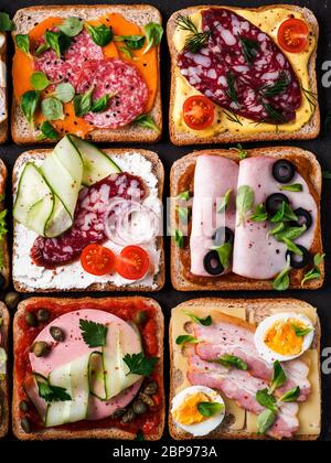 Satz von acht verschiedenen Sandwiches mit Fleisch in quadratische Form. Top View oder flach. Sortiment Fleisch Toast auf schwarzem Hintergrund. Idee, kreative Konzept Stockfoto