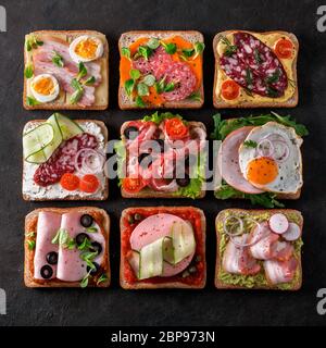 Satz von acht verschiedenen Sandwiches mit Fleisch in quadratische Form. Top View oder flach. Sortiment Fleisch Toast auf schwarzem Hintergrund. Idee, kreative Konzept Stockfoto