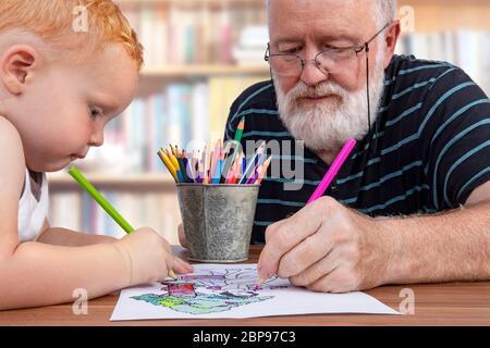 Opa zusammen arbeiten und Färbung auf einer Zeichnung mit seinen kleinen Enkel Stockfoto