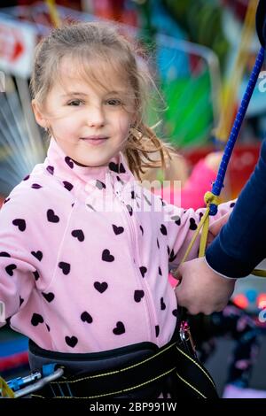 Ein kleines Mädchen in Sicherheit Kabelbaum und Seilen vor dem Springen auf einem Trampolin in einen Vergnügungspark Stockfoto