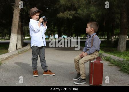 Zwei Kaukasischen jungen Brüder in Vintage Kleidung. Eine auf einem alten Koffer sitzt, übernimmt die andere Bilder von ihm auf einem retro Kamera Stockfoto