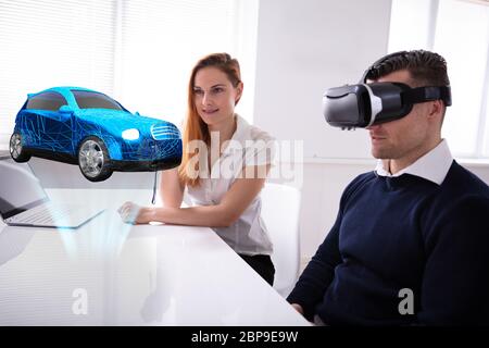 Mann, der VR-Headset im Auto Modell sitzen in der Nähe von weiblichen Agent Stockfoto