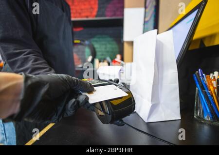 Zahlung mit Kreditkarte an eine Kasse im Einzelhandel. Lokale Unternehmen, kleine Geschäfte und mit POS-Terminal-Konzept Stockfoto