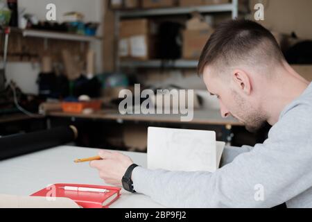 Porträt eines Bekleidungsdesigners oder Ingenieurs in einer generischen Werkstatt. Kleinunternehmen, lokaler Unternehmer, Modeentwicklungskonzept Stockfoto