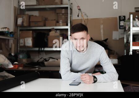 Männliches Porträt in einem allgemeinen Lager. Unternehmer, Designer oder Ingenieur, der in der Werkstatt eines lokalen Geschäftsbetriebs auftritt Stockfoto