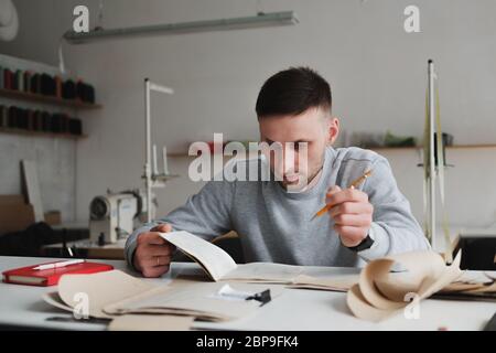 Mann, der in einer generischen Werkstatt Ingenieursarbeit leistet oder Arbeit leitet. Lokale Kleinunternehmen, Kleidung Designer Porträt Stockfoto