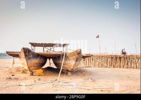 Boot auf dem Sand bei Ko Pen mit einer Bambusbrücke in der Ferne. Kambodscha, Südostasien Stockfoto