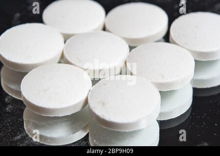 Pillen auf einer Spiegelfläche mit schwarzem Hintergrund gestapelt. Gesundheits- und medizinische Themen Stockfoto