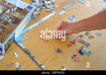 Puzzle wird von einer Frau wieder zusammengebaut. Referenzbild zu Hand und Kanten fast vollständig. Stockfoto
