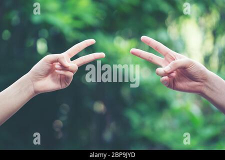 Paar spielen Rock Paper Scissors hand Spiel der Natur grüner Hintergrund Stockfoto