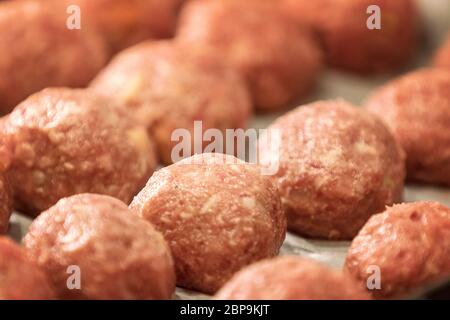 Rohe Knödel auf Tablett. Frisches Hackfleisch in Form von Kugeln mit Pfeffer, Salz. Künstliches Fleisch Konzept, Soft Focus. Stockfoto