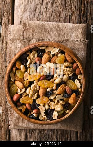 Gesunde Trail Mix Snack aus Nüssen (Walnuss, Mandel, Erdnuss) und getrockneten Früchten (Rosinen, Sultana) in Holzschale, fotografiert Overhead (Selective Focu Stockfoto