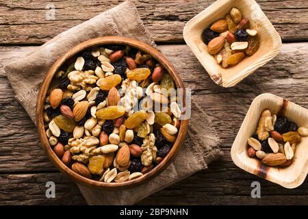 Gesunde Trail Mix Snack aus Nüssen (Walnuss, Mandel, Erdnuss) und getrockneten Früchten (Rosinen, Sultana) in Holzschale, fotografiert Overhead (Selective Focu Stockfoto