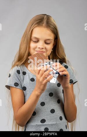 Die 10-jährige Mädchen schaut freudig an eine Tafel Schokolade Stockfoto