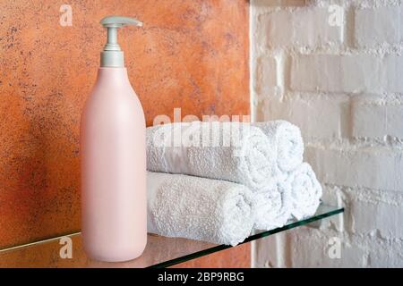 Shampoo Balsam Seife kosmetische Produkt Flasche für Haarpflege, Körperhygiene und Handtuchrollen auf Bad Regal. Weiße Frottee-Handtücher im Schönheitssalon. Spa Stockfoto