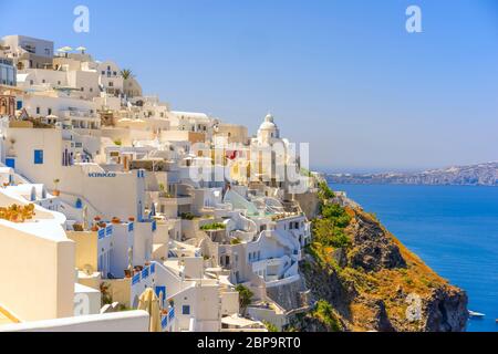 Die Sonne scheint auf den idyllischen Kirchen und Häusern, die am Rand der Caldera in Thira, Santorini, errichtet wurden Stockfoto