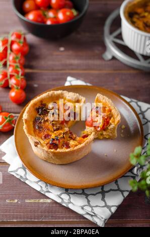 Mini-Quiche mit Würstchen, Mini-Tomaten und Kräutern Stockfoto