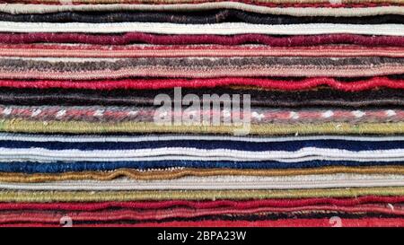 Stapel von alten türkischen Teppichen. Schichten von bunten Teppichen. Gewebte Textur. Kanten von ethnischen Teppichen. Traditionelle asiatische Fußmatten. Türkischer Basar, Backdr Stockfoto
