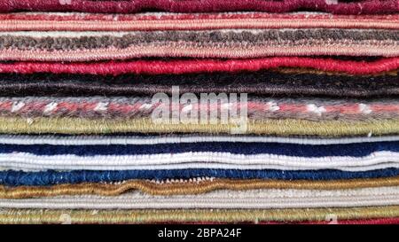Haufen von alten türkischen Teppichen. Schichten von bunten Teppichen. Gewebte Textur. Kanten von ethnischen Teppichen. Traditionelle asiatische Fußmatten. Türkischer Basar Backdro Stockfoto
