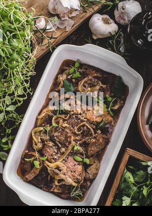 Schweinefleisch in einem Backofen mit Äpfel würfeln, Knoblauch, Kräuter und Zwiebeln Stockfoto