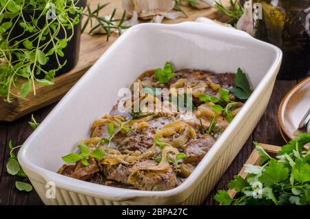 Schweinefleisch in einem Backofen mit Äpfel würfeln, Knoblauch, Kräuter und Zwiebeln Stockfoto