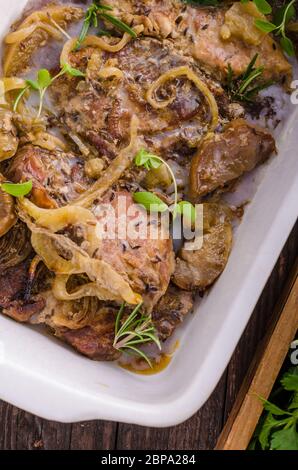 Schweinefleisch in einem Backofen mit Äpfel würfeln, Knoblauch, Kräuter und Zwiebeln Stockfoto