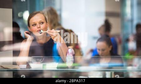 Hübsche, junge Frau Sushi essen in einem Restaurant, in der Mittagspause, genießen das Essen, Pausen für eine Weile aus ihrem ereignisreichen Leben (Corporate/Büro Stockfoto