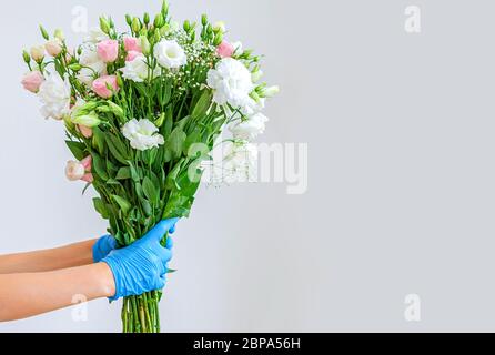 Blumenstrauß Lieferung. Kurier hält Ranunculus in medizinischen Handschuhen. Lieferung von Blumen in medizinischen Handschuhen Stockfoto
