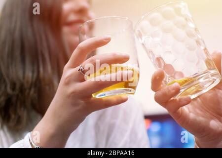 Trinken Sie Craft-Bier mit einem Freund, klirrrend Gläser. Zwei Hände halten zwei Gläser Bier Friendship Concept. Junge nette Mädchen Freunde halten Gläser toge Stockfoto