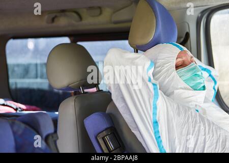 Müde Notarzt aus dem Rettungsdienst schläft in einem Krankenwagen im Bereitschaftszustand in Schutzkleidung Stockfoto