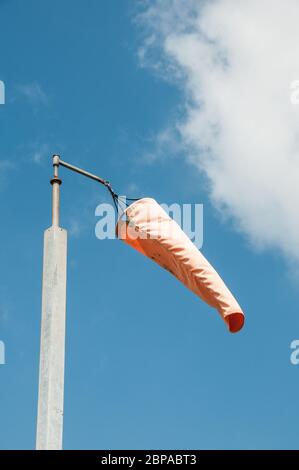 Rund um Großbritannien - Wind Socke gegen einen blauen Himmel mit weißen flauschigen Wolken Stockfoto