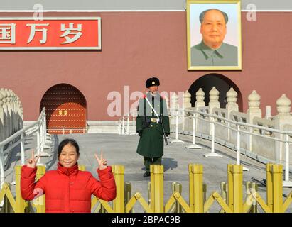 Peking / China - 25. Januar 2014: Mädchen posiert für ein Foto, als chinesischer Soldat Wache vor dem Haupttor der Verbotenen Stadt mit Porträt o steht Stockfoto