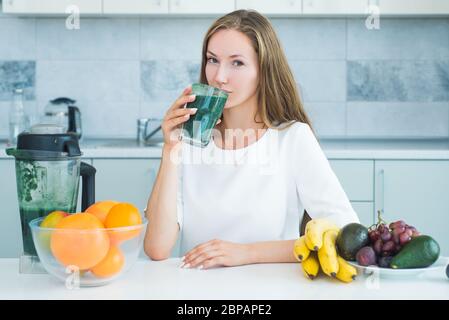 Frau, die grüne Spirulina in einer weißen Küche trinkt. Entgiftung. Perfekte Körper und Kalorien. Vegane Mahlzeit Diät zu Hause. Nahrungsergänzungsmittel. Bio-Lebensmittel und Vitami Stockfoto