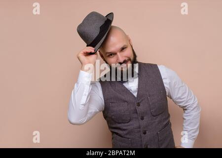 Schöner Mann mit Hut lächelt und grült. Hallo meine Freunde Konzept. Studio auf farbigem Hintergrund aufgenommen. Stockfoto