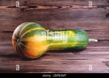 Gelb-grüner länglicher Kürbis, natürlicher Holzhintergrund, Diätnahrung, Halloween Nahaufnahme Stockfoto