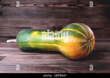 Gelb-grüner länglicher Kürbis, natürlicher Holzhintergrund, Diätnahrung, Halloween Nahaufnahme Stockfoto