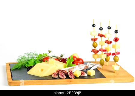 Canapes von Oliven, Chorizo, Salami, Käse und Apfelscheiben auf den dekorativen Holzstäbchen. Weißer Hintergrund. Gesunde Lebensmittel für Snacks. Stockfoto