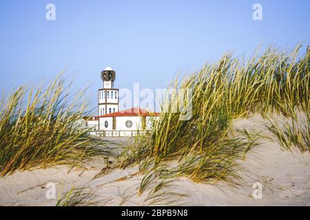 Die Kirche und der Turm der Costa Nova sind bei Tageslicht von Sanddünen und Hafer umgeben. Stockfoto