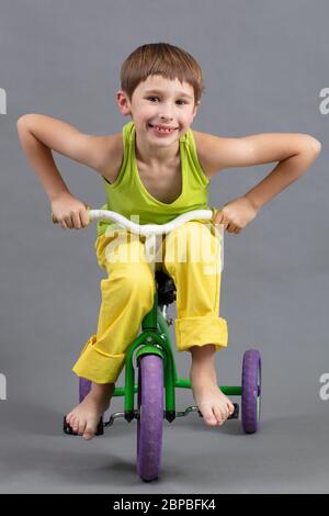 Aufrecht fährt ein Kind in heller Kleidung barfuß ein Kinderfahrrad. Stockfoto