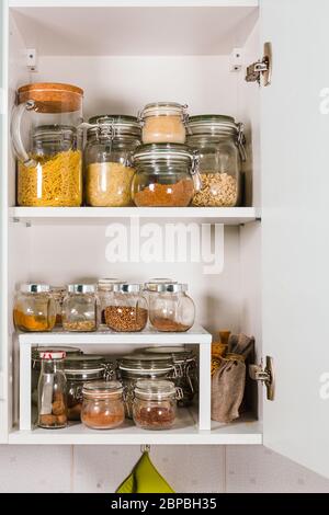 Verschiedene Getreide und Samen in Gläsern auf den Regalen in der Küche Stockfoto
