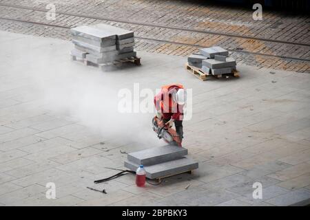 Belgrad, Serbien - 18. Mai 2020: Bauarbeiter schneiden Pflastersteine mit Benzinstein-Scheibenfräser, hohe Winkelansicht Stockfoto