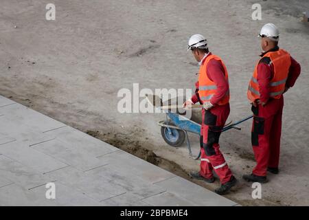 Belgrad, Serbien - 18. Mai 2020: Bauarbeiter arbeiten mit Schaufel und Schubkarre, hohe Winkelansicht Stockfoto