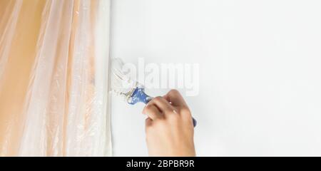 Menschliche Hand malt mit einem Pinsel auf den Rand eines Türrahmens Handwerk Renovierung Übergabe Wohnung Schaden frisch lackiert weiße Wand-Werkzeuge tun es sich Stockfoto