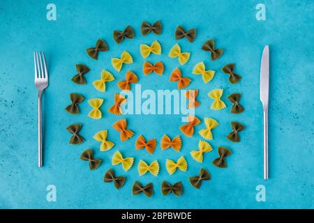 Rohe bunte Pasta abgerundet als Teller mit Gabel und Messer Stockfoto